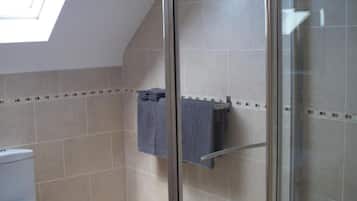 A bathroom with a glass shower enclosure, a toilet, and a towel rack.