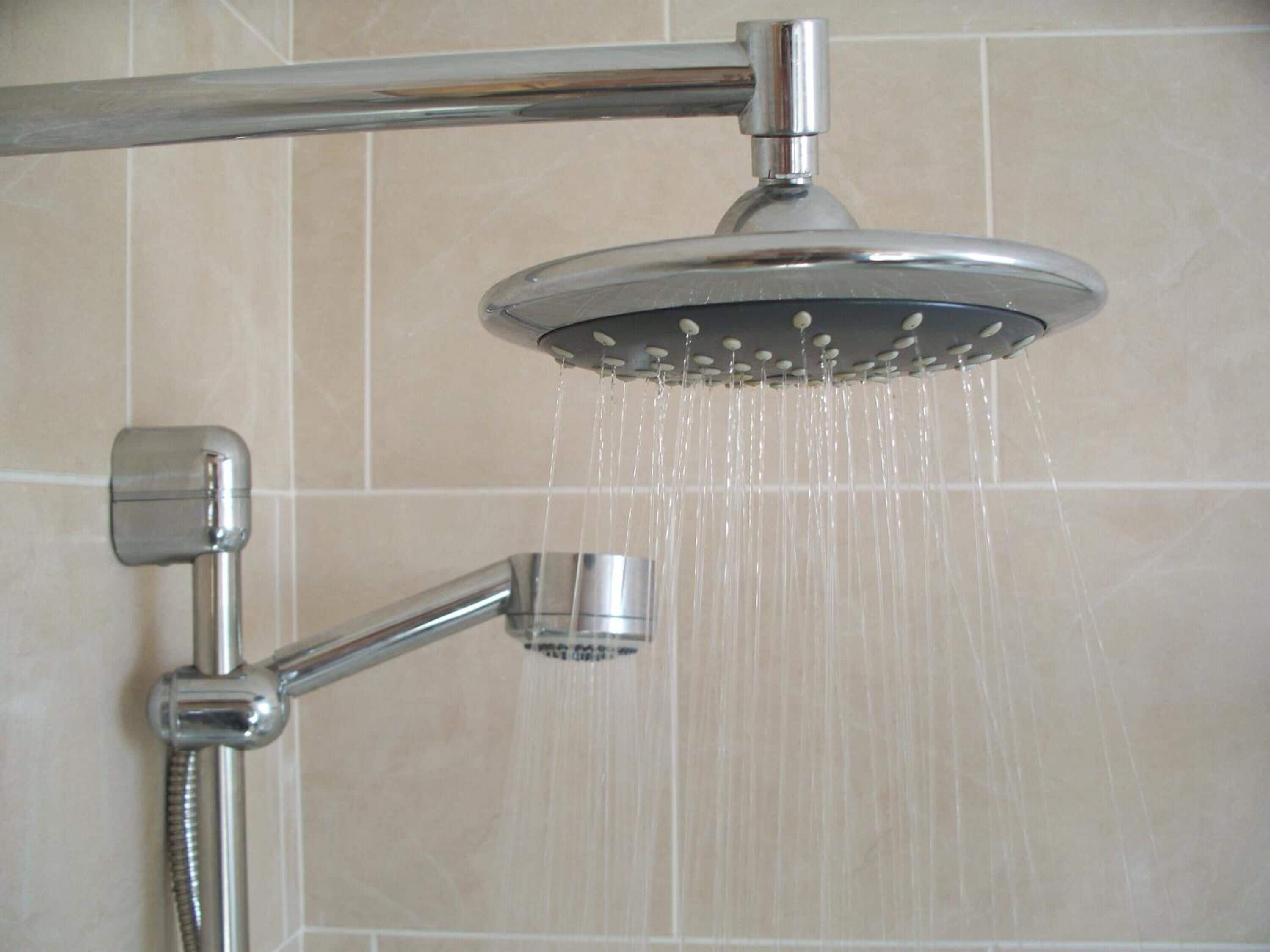 A shower with multiple heads, including a handheld showerhead and a fixed overhead showerhead.