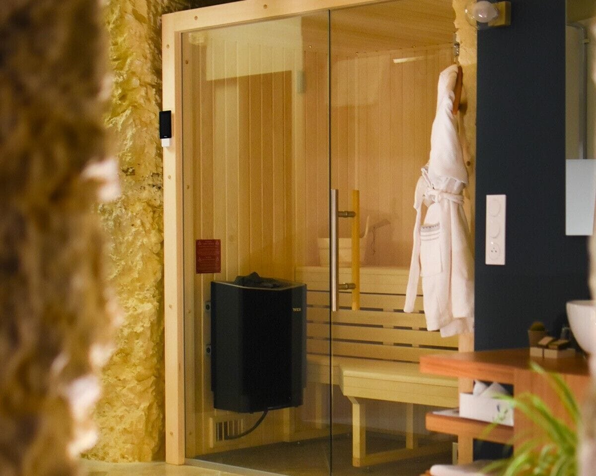 Una sala de sauna con un banco de madera, una puerta de vidrio y una toalla colgada en la pared.