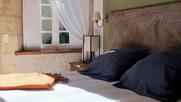 Une chambre à coucher avec un lit, une fenêtre avec des rideaux, une table de chevet et une lampe.