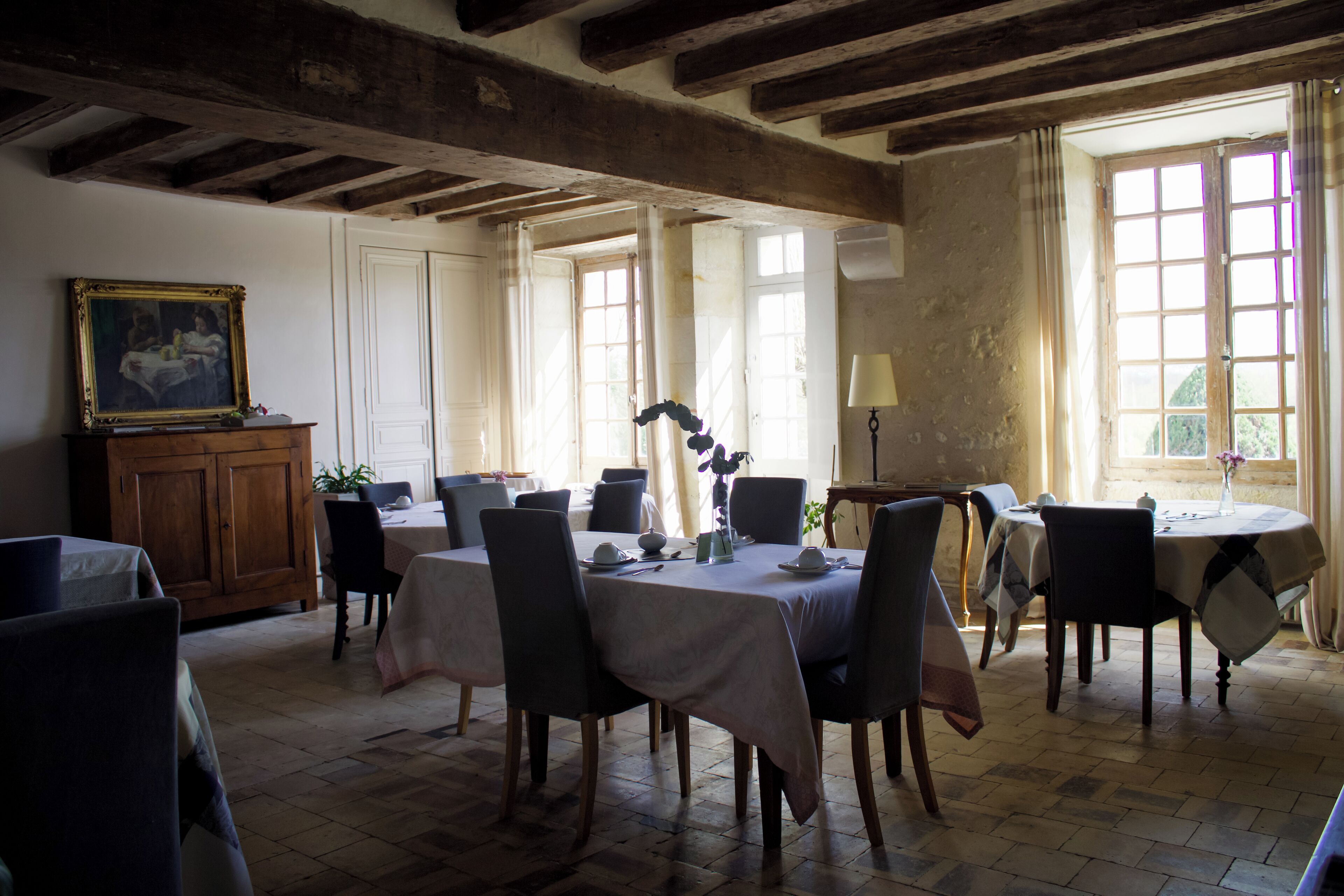Un comedor con techo de madera, ventanas amplias y un cuadro en la pared.