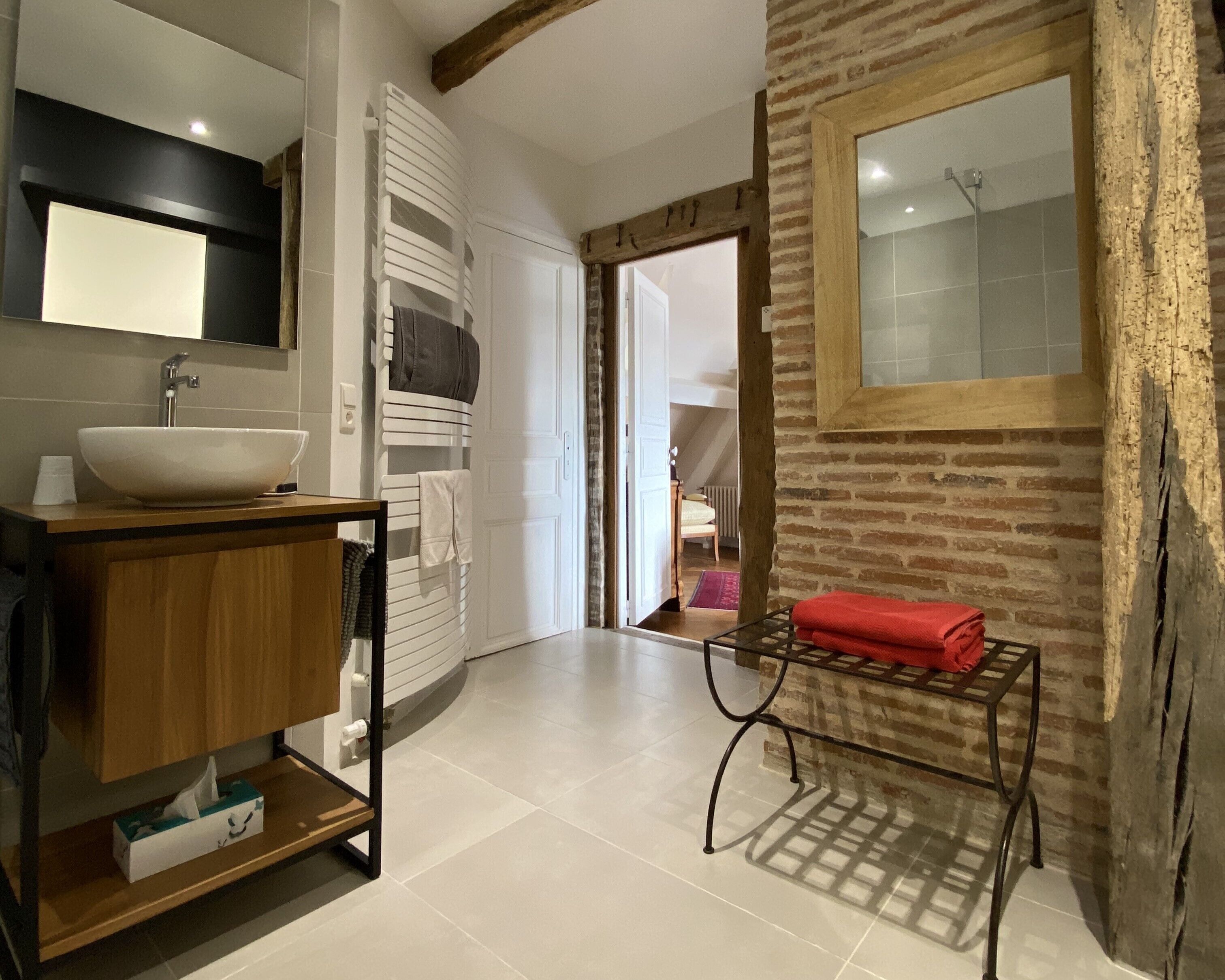 A modern bathroom with a large white sink, wooden vanity, and a glass shower enclosure.