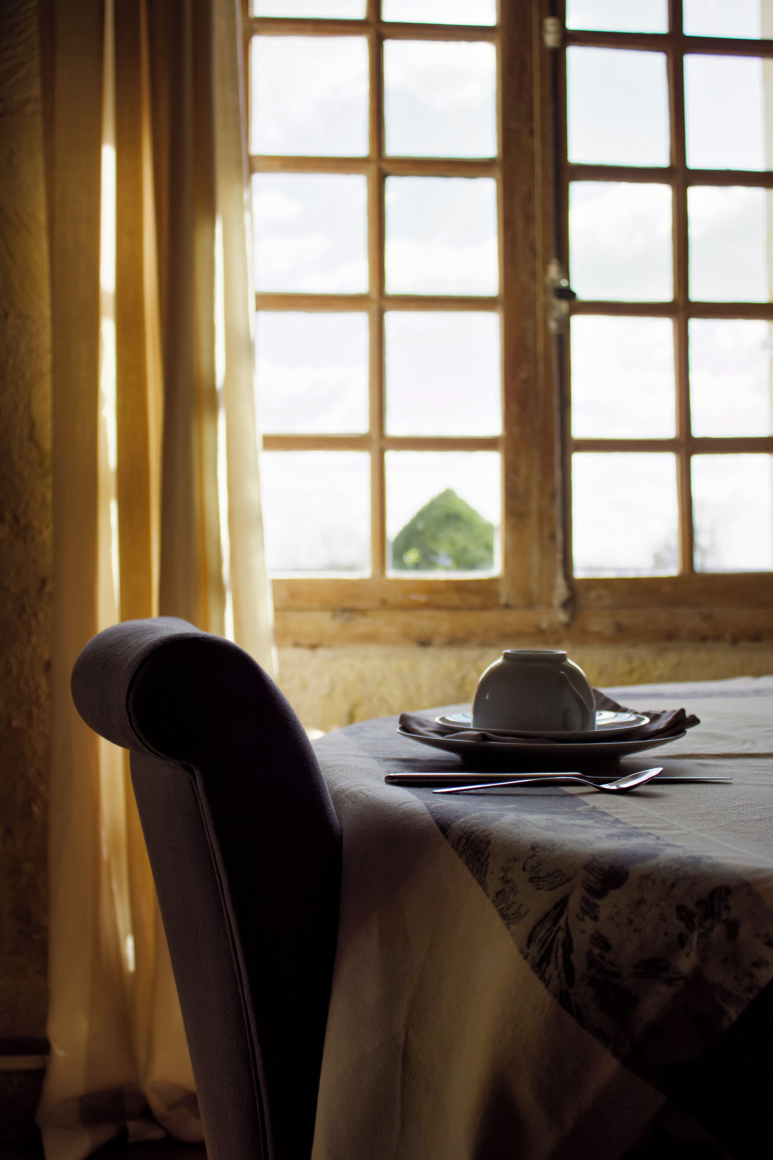 A dining table with a white tablecloth, a chair, and a cup and saucer set.