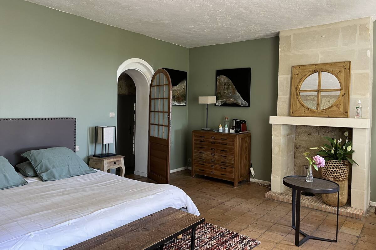 Une chambre à coucher avec un lit, une commode et une cheminée.
