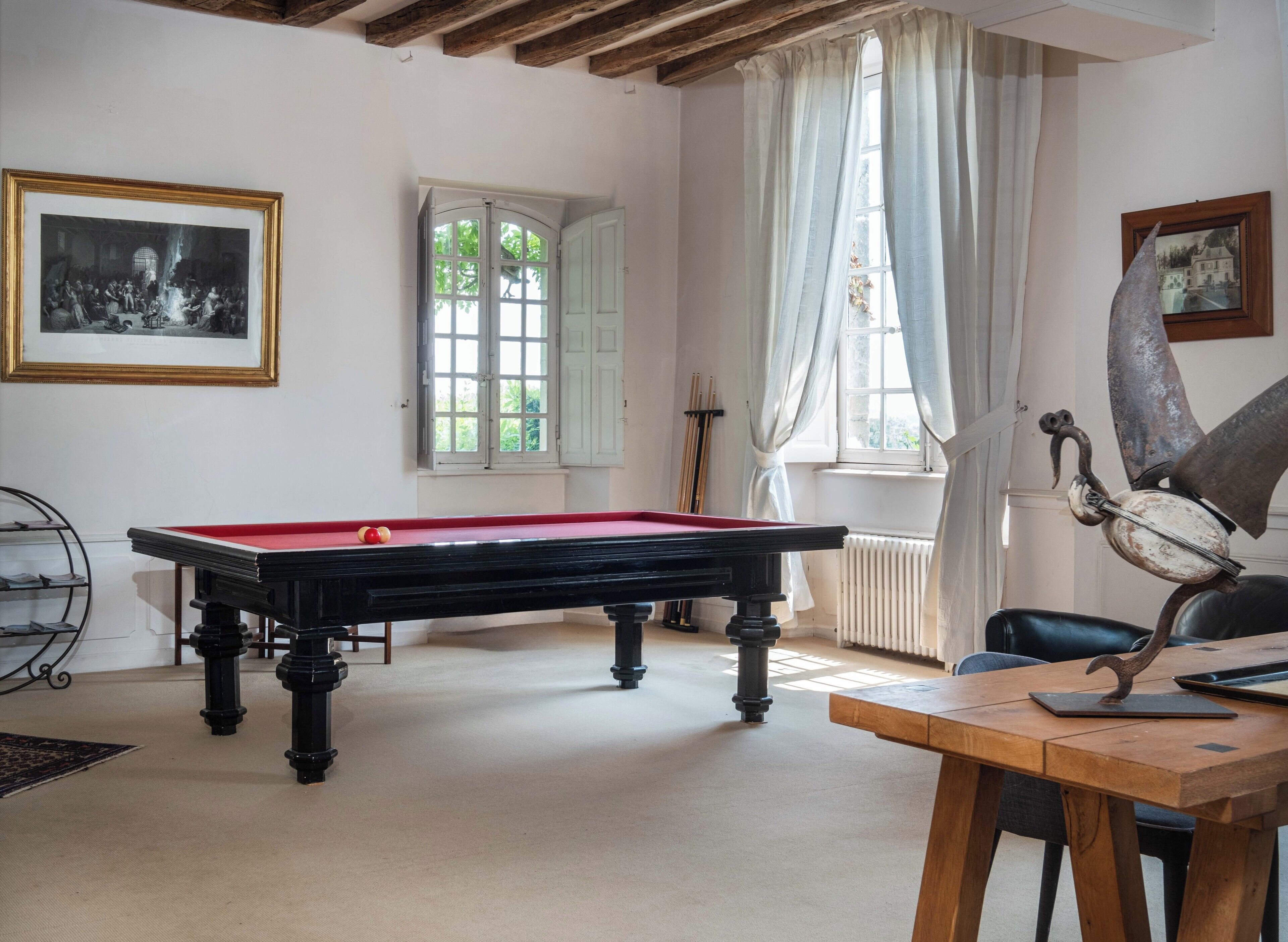 A room with a pool table, a billiards rack, a framed picture, a window with curtains, and a statue.