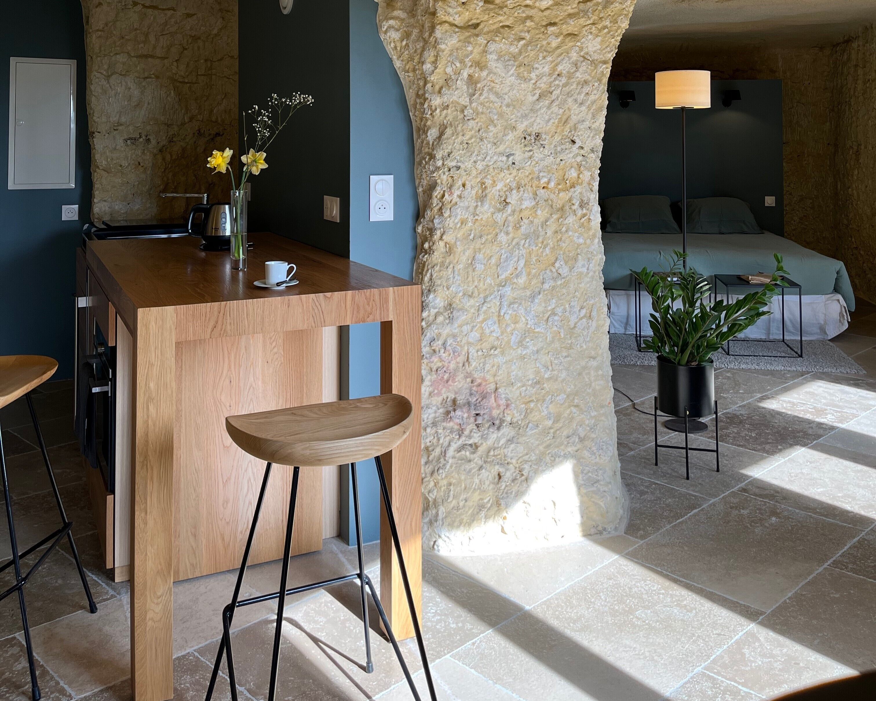 Una cocina moderna con barra de madera, un jarrón con flores y una cafetera.