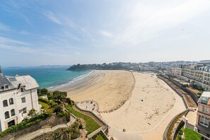 A coastal view with a sandy beach, a promenade, and buildings along the shore. - Résidence Le Crystal (Dinard)