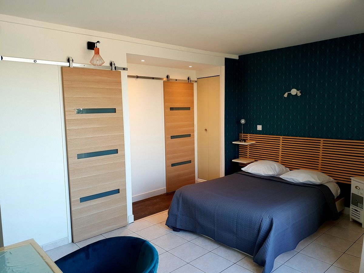 Un dormitorio con cama, armario, escritorio y silla.