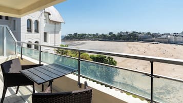 Ein Balkon mit Blick auf einen Strand und ein Gebäude mit Bogenfenstern.