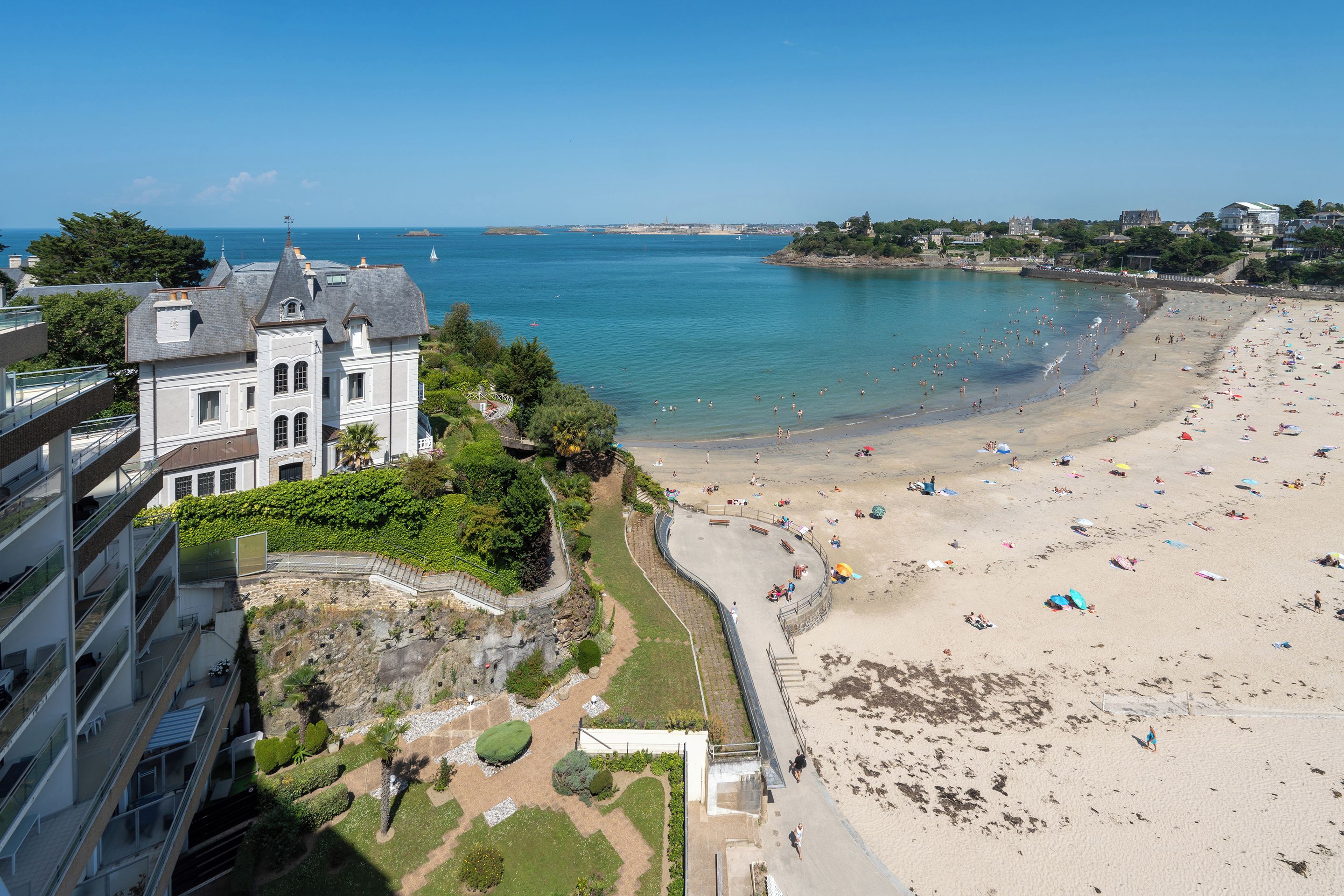 A coastal hotel with a beach view, a landscaped garden, and a large pool area.