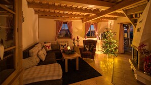 Uma sala de estar aconchegante com teto de madeira, um sofá, uma poltrona, uma mesinha e um pinheiro de Natal.