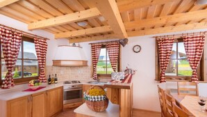 Uma cozinha com armários de madeira, fogão e área de jantar com mesa e cadeiras.