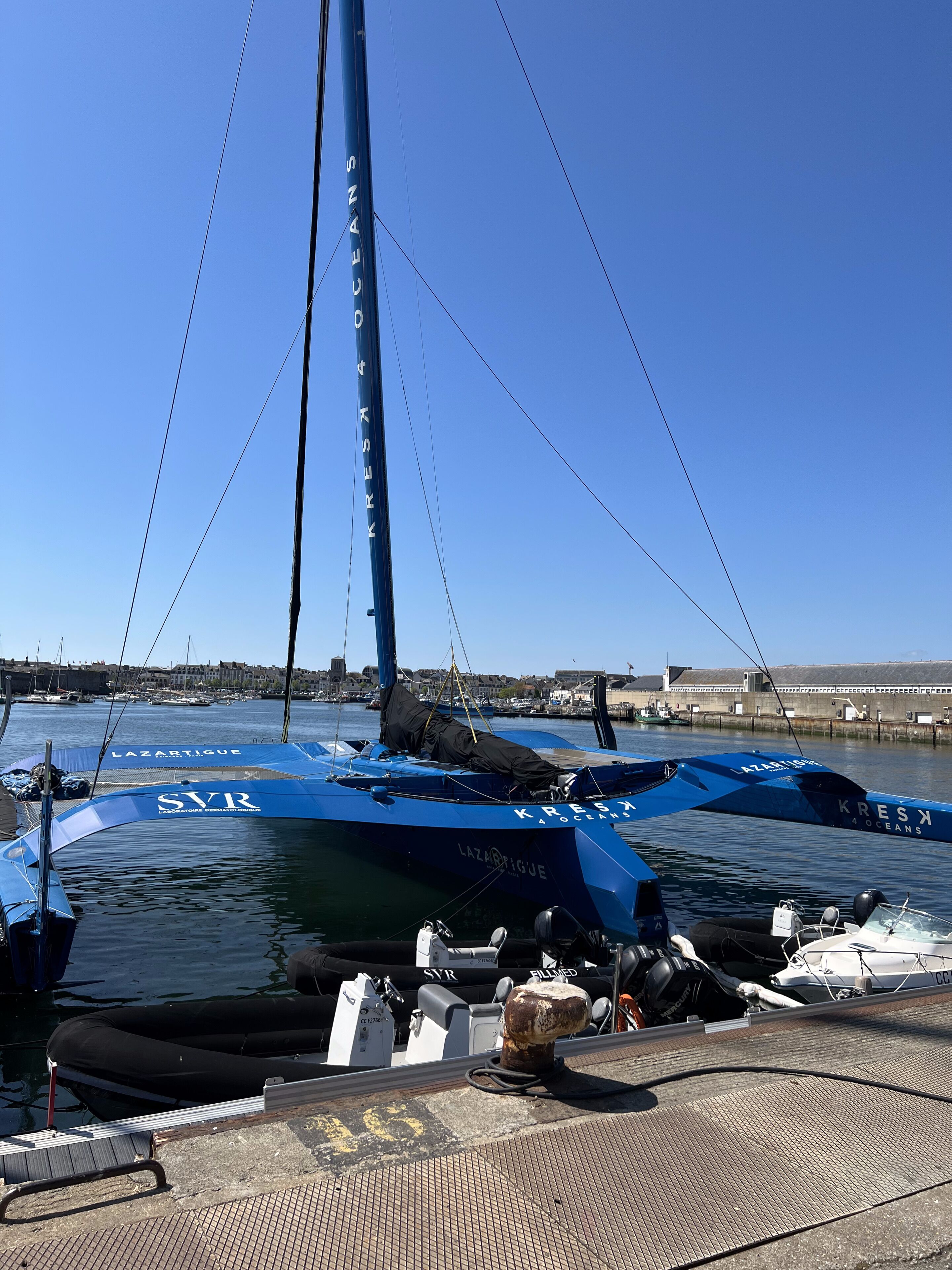 Un port de plaisance avec des bateaux amarrés, un ciel dégagé et une vue lointaine sur la ville.