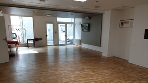 Un pasillo amplio con suelo de madera, un perchero y una mesa con sillas.