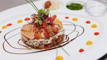 A plated dish with a variety of ingredients, garnished with herbs, and accompanied by small bowls of sauces.
