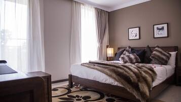 A hotel room with a bed, a desk, and a chair.