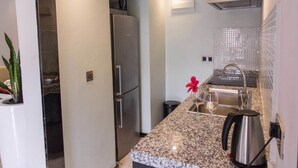 Una cocina moderna con encimera de granito, electrodomésticos de acero inoxidable y un lavamanos pequeño.