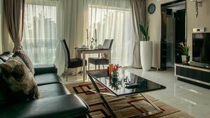 Una sala de estar moderna con una mesa de centro de vidrio, sofá de cuero y un comedor con mesa y sillas.