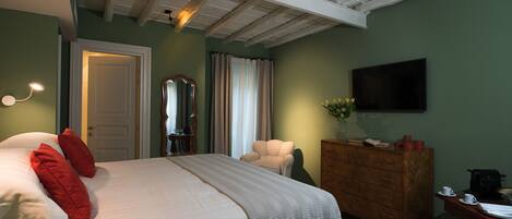 Un dormitorio con cama, cómoda, silla, espejo y televisión en la pared.