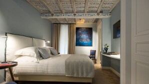 Een hotelkamer met een groot bed, een bureau, een stoel en een schilderij aan de muur.