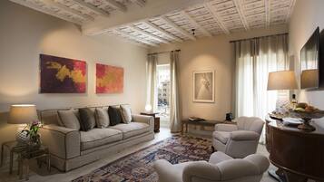 A living room with a sofa, armchairs, a coffee table, and a patterned rug.