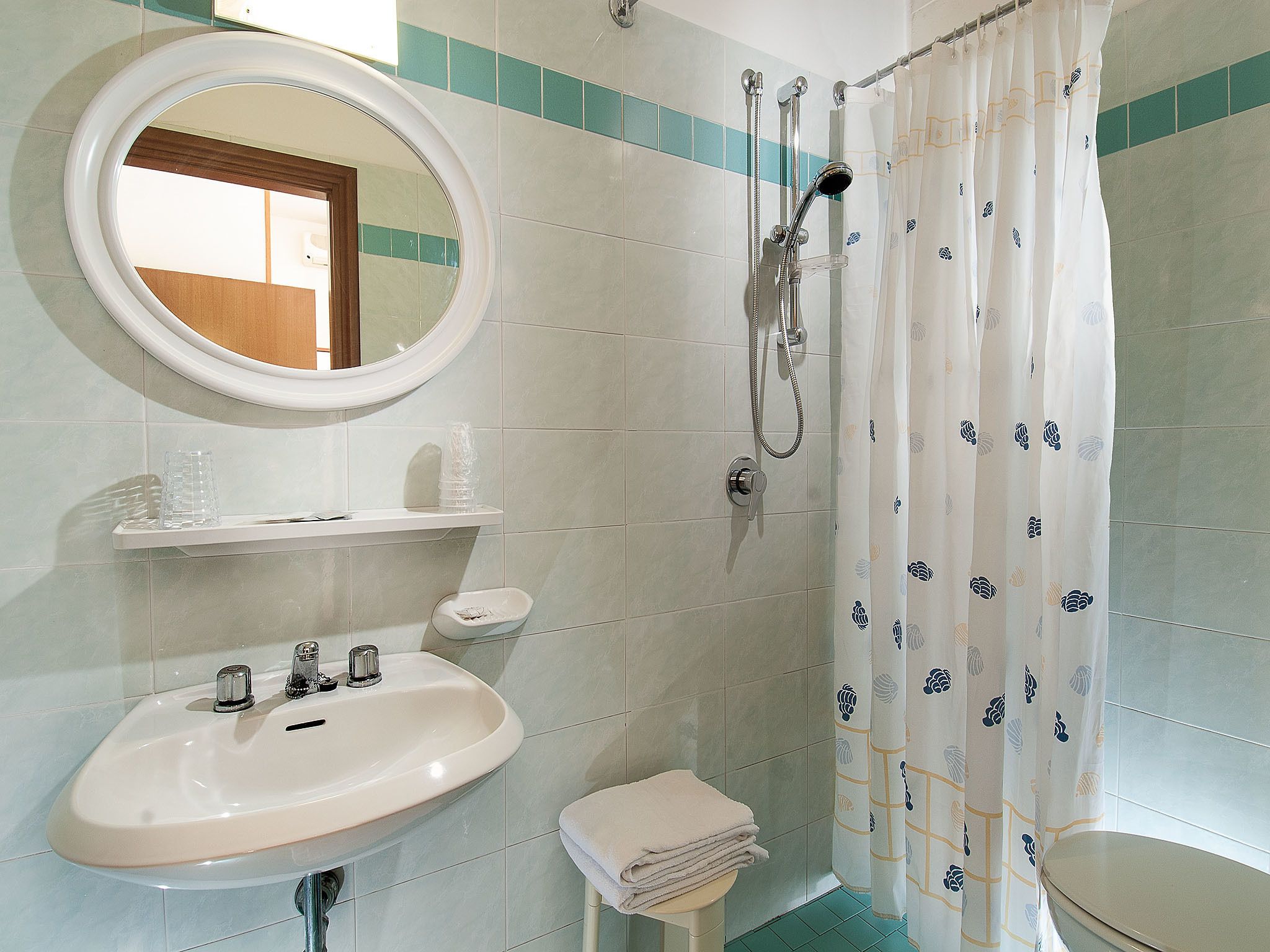 A bathroom with a sink, mirror, shower, and toilet.
