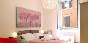 Una camera da letto con un letto, comodini, un quadro, una finestra e vista su un edificio.