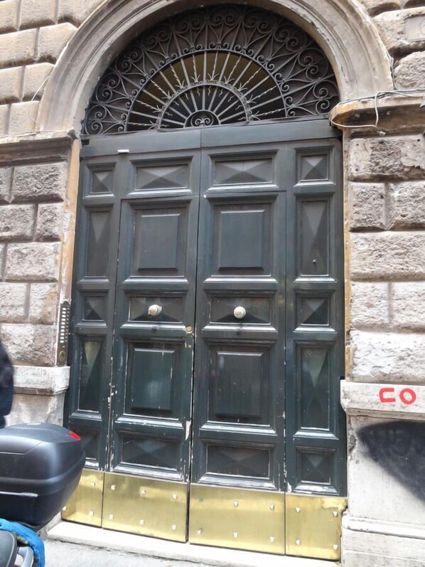 Una doble puerta con una reja metálica sobre ella, ubicada en un edificio de piedra.