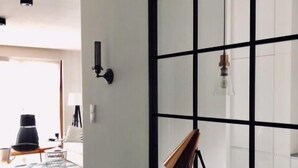 A modern room with a large window, a desk with a lamp, and a pair of shoes on the desk. - ShortStayPoland Kieslowskiego - B41 (Warsaw)