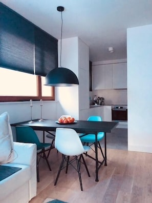 A modern dining area with a black table, blue chairs, and a white sofa.