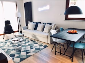 A modern living room with a sofa, coffee table, and dining table.