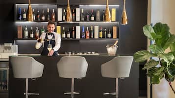 A bar area with a bartender, shelves of wine bottles, and bar stools.