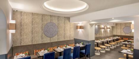 Un restaurante moderno con una zona de mesas centrales, mesas individuales y un reloj distintivo en la pared.