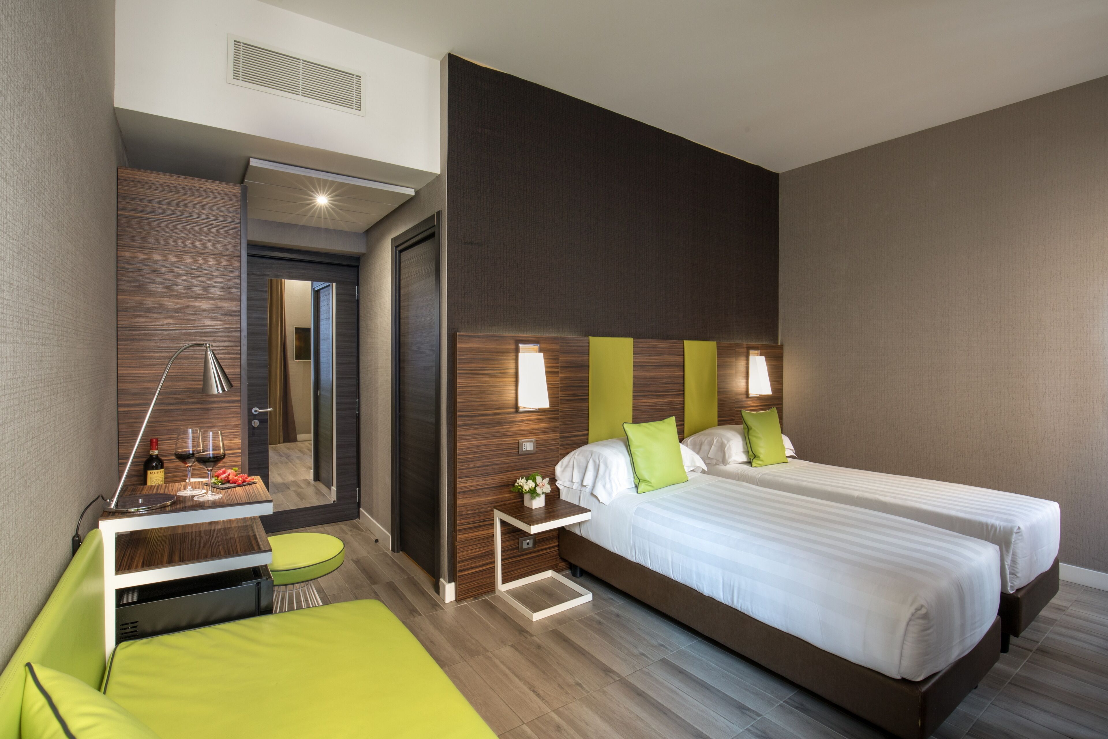 Una habitación de hotel moderna con una cama grande, un escritorio pequeño y un sofá verde.