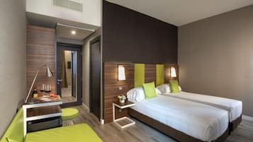 Une chambre d’hôtel moderne avec un grand lit, un petit bureau et un canapé vert.