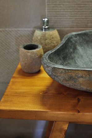 A wooden table with a stone bowl and a smaller stone container. - Sand Lily Mykonos (Mykonos)