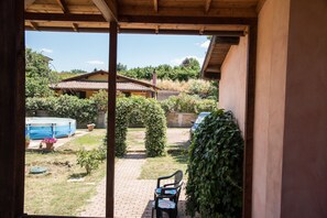 Un patio cubierto con vistas a una casa, una piscina y un coche aparcado fuera.