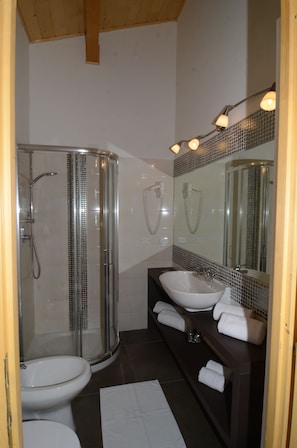 A modern bathroom with a glass shower enclosure, a white sink, and a large mirror. - IL Rifugio dell'aquila (Ventasso)