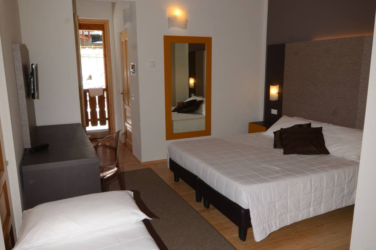 A bedroom with two beds, a desk, and a chair.
