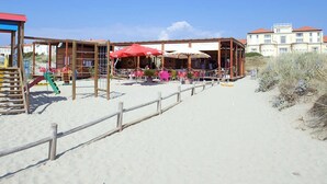 Een restaurant aan het strand met terras, een speeltuin en een houten hek.