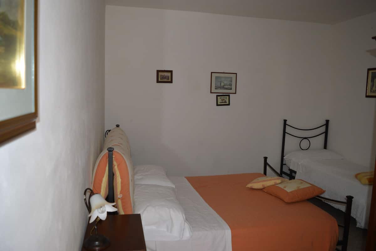 A bedroom with two beds, a nightstand, a lamp, and framed pictures on the wall.