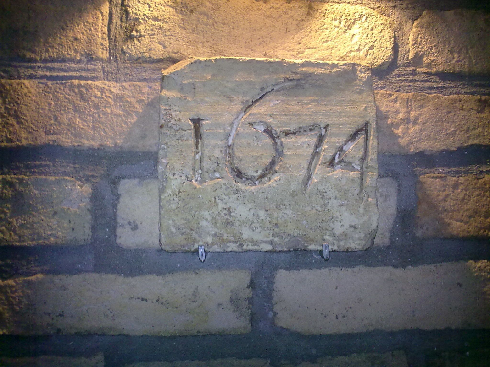Tiiliseinään kiinnitetty kivilaatta, jossa on kaiverrus ”1674”.