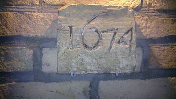 Tiiliseinään kiinnitetty kivilaatta, jossa on kaiverrus ”1674”.
