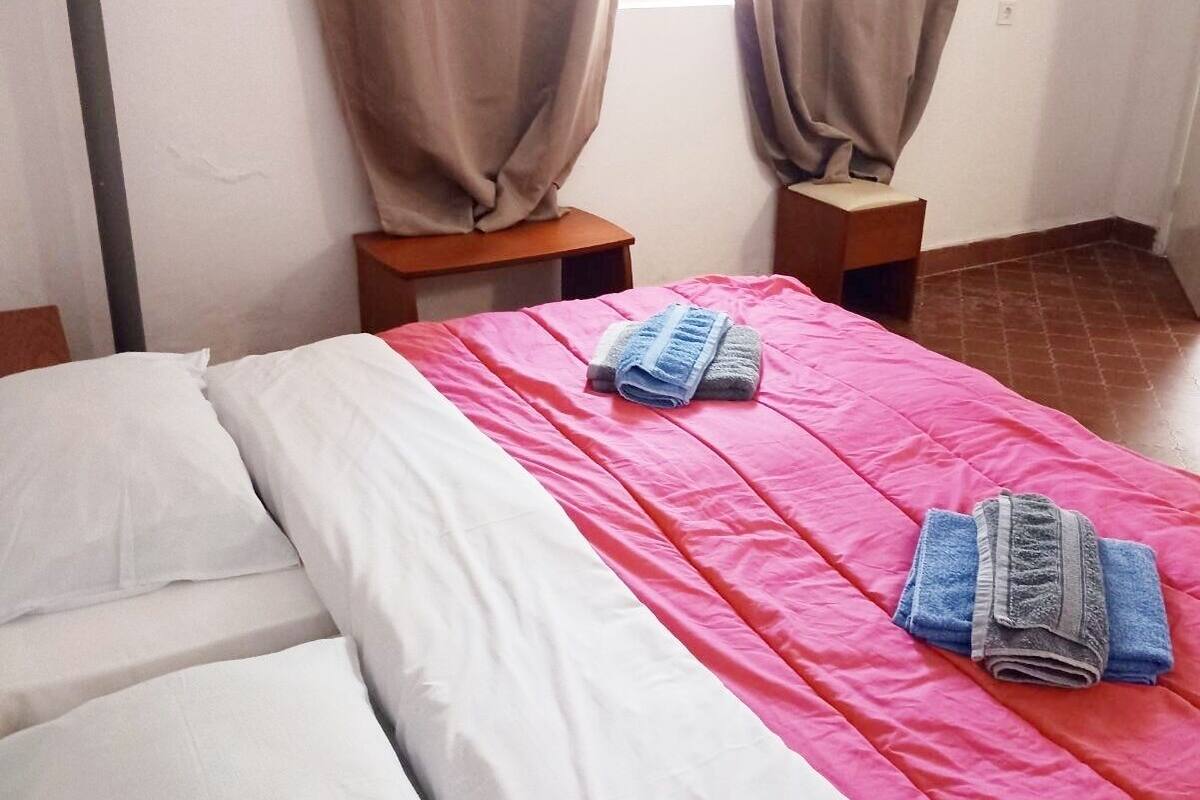 A bedroom with a bed, two nightstands, and a window with curtains.