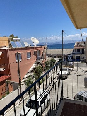 A residential area with a balcony overlooking a street, solar panels on a building, and a clear view of the sea. - Avra Boutique (Corfu)