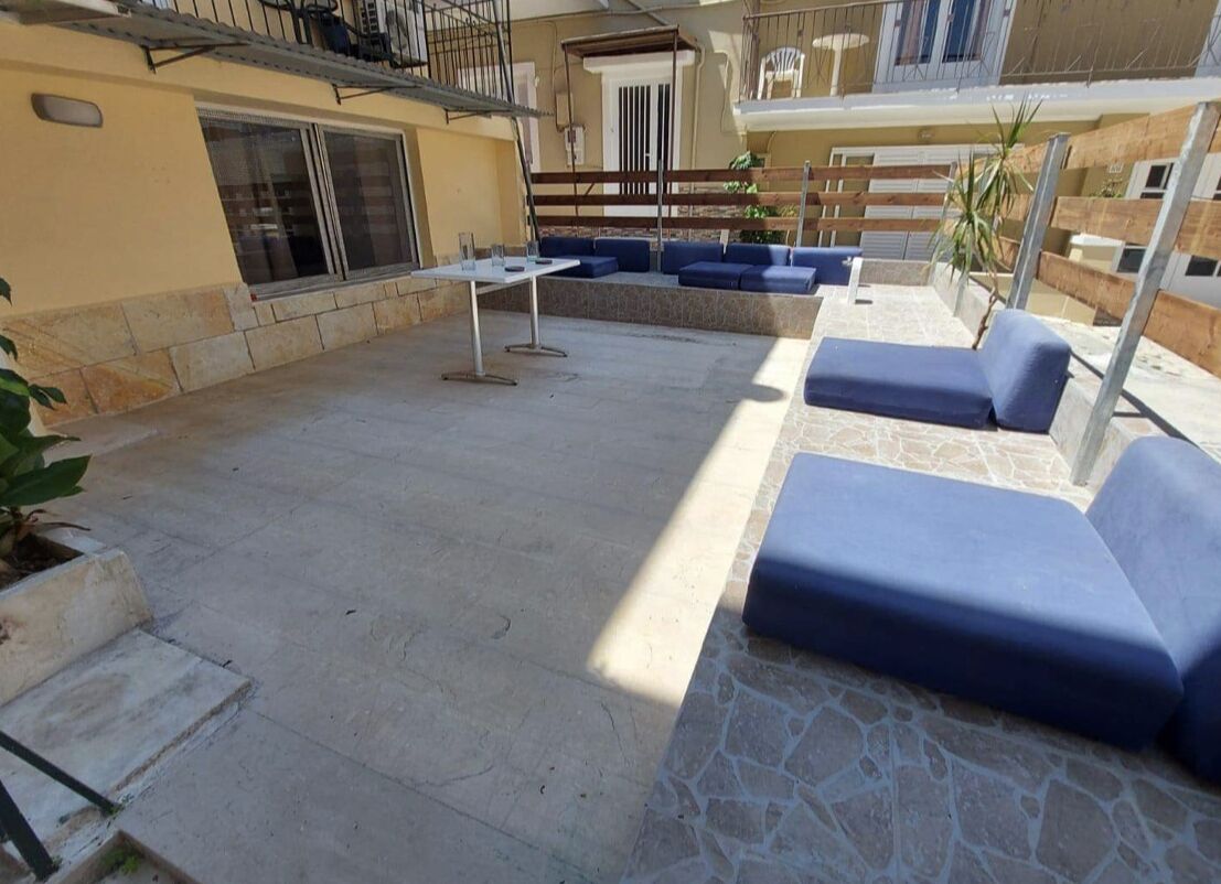 An outdoor patio with stone flooring, blue cushioned seating, and a table.
