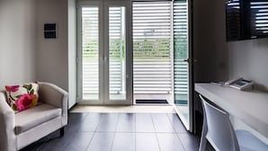 Una habitación moderna con sofá, escritorio y puerta corrediza de vidrio que da a un balcón.