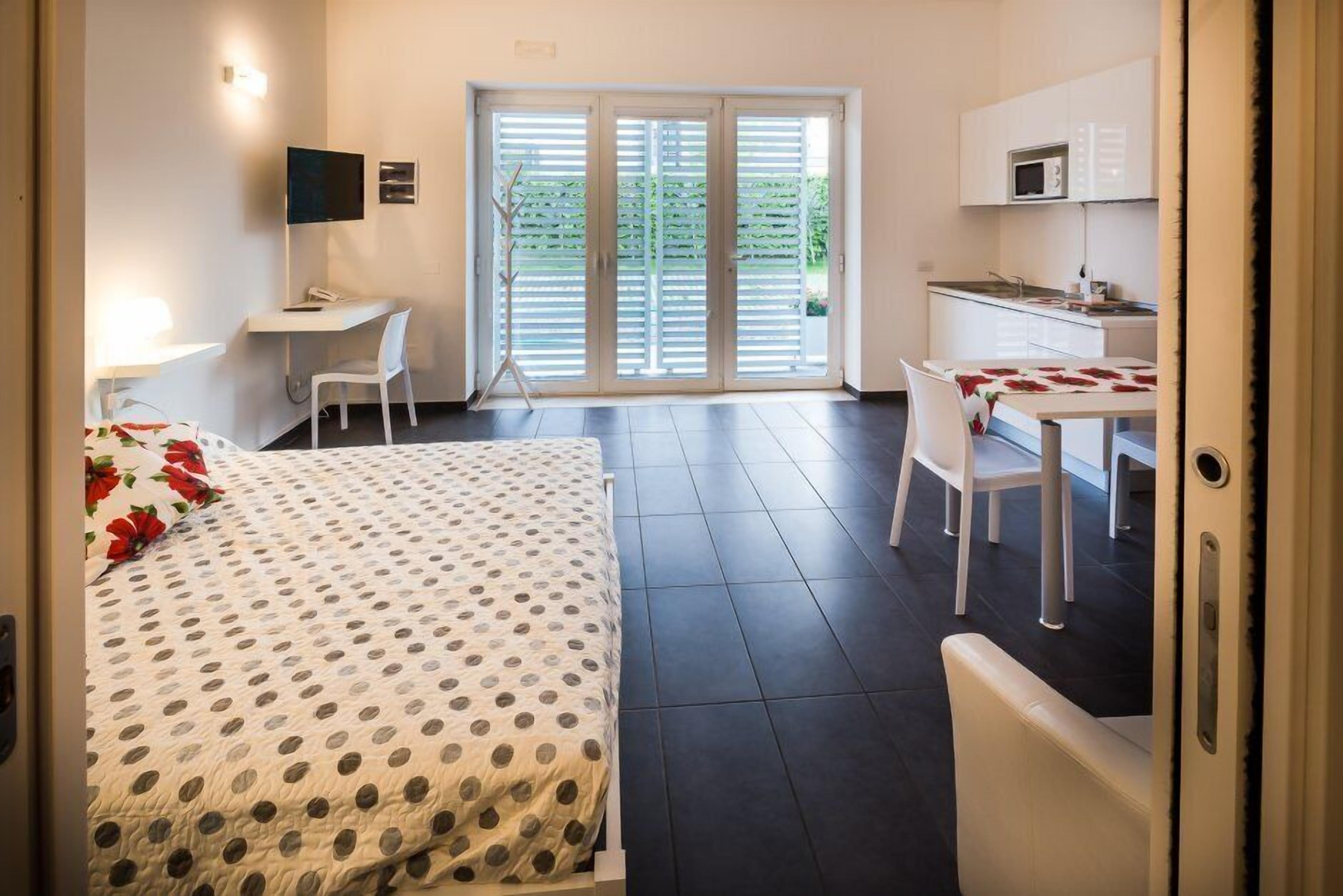 Ein Hotelzimmer mit Bett, Schreibtisch, Stuhl und einer Küchenzeile.