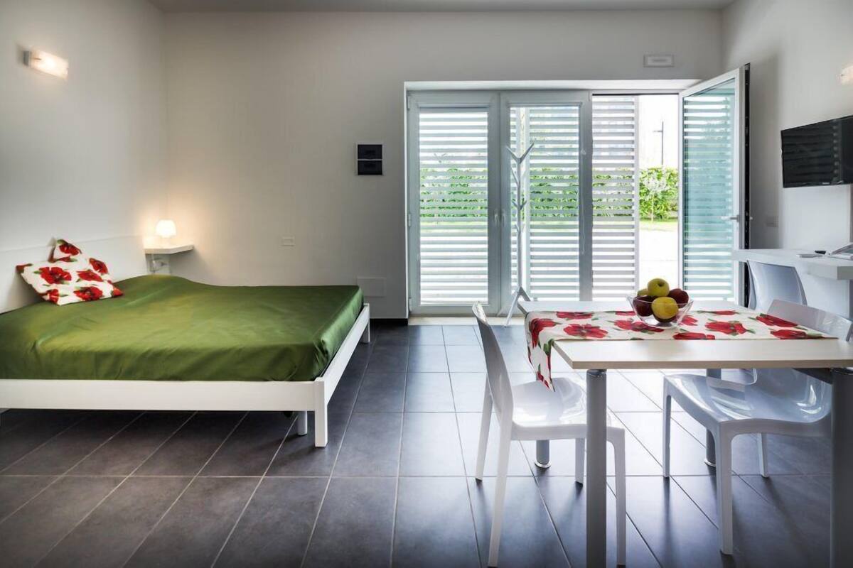 A modern bedroom with a bed, a table with fruit, and a TV.