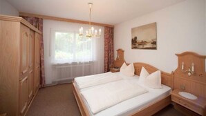 Un dormitorio con cama doble, armario de madera, radiador, candelabro y un cuadro en la pared.